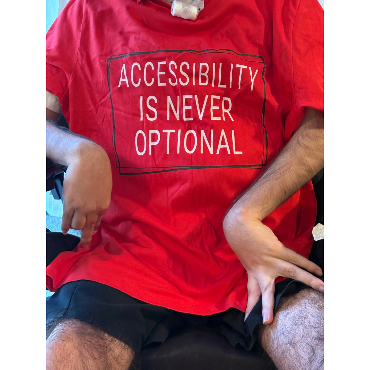 a man in a wheelchair wearing a dtf printed tshirt that says accessibility is never optional