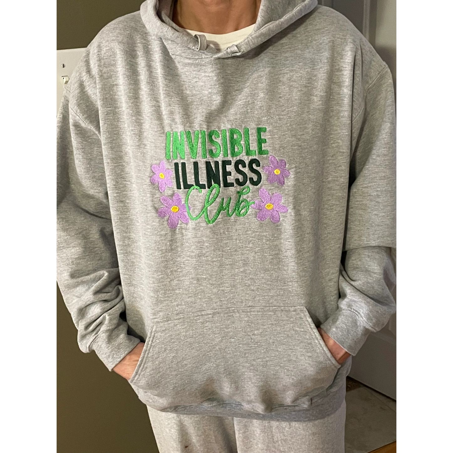Gray hoodie with 'Invisible Illness Club' text and flowers on a plain background