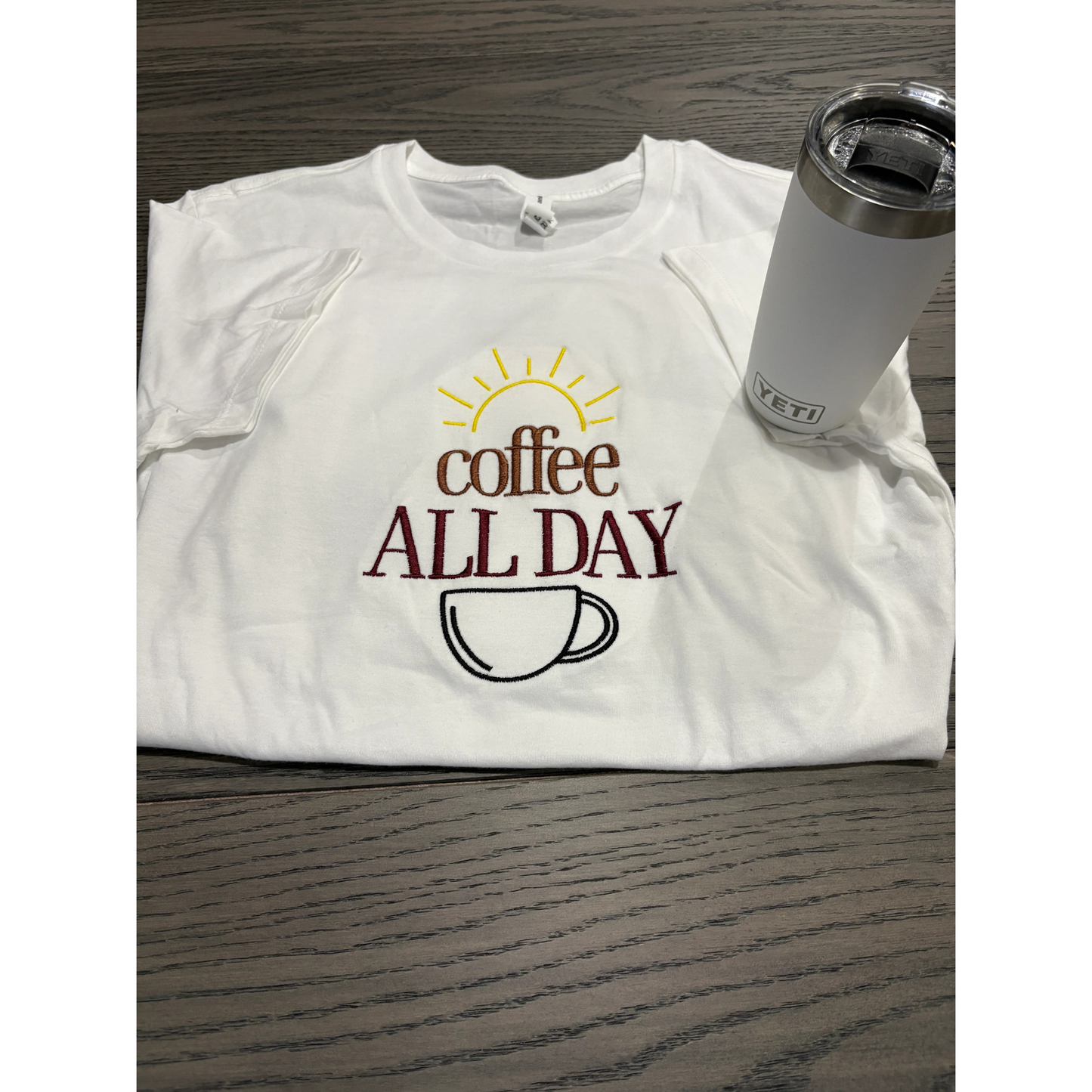 White t-shirt with 'Coffee All Day' design and a Yeti tumbler on a wooden surface
