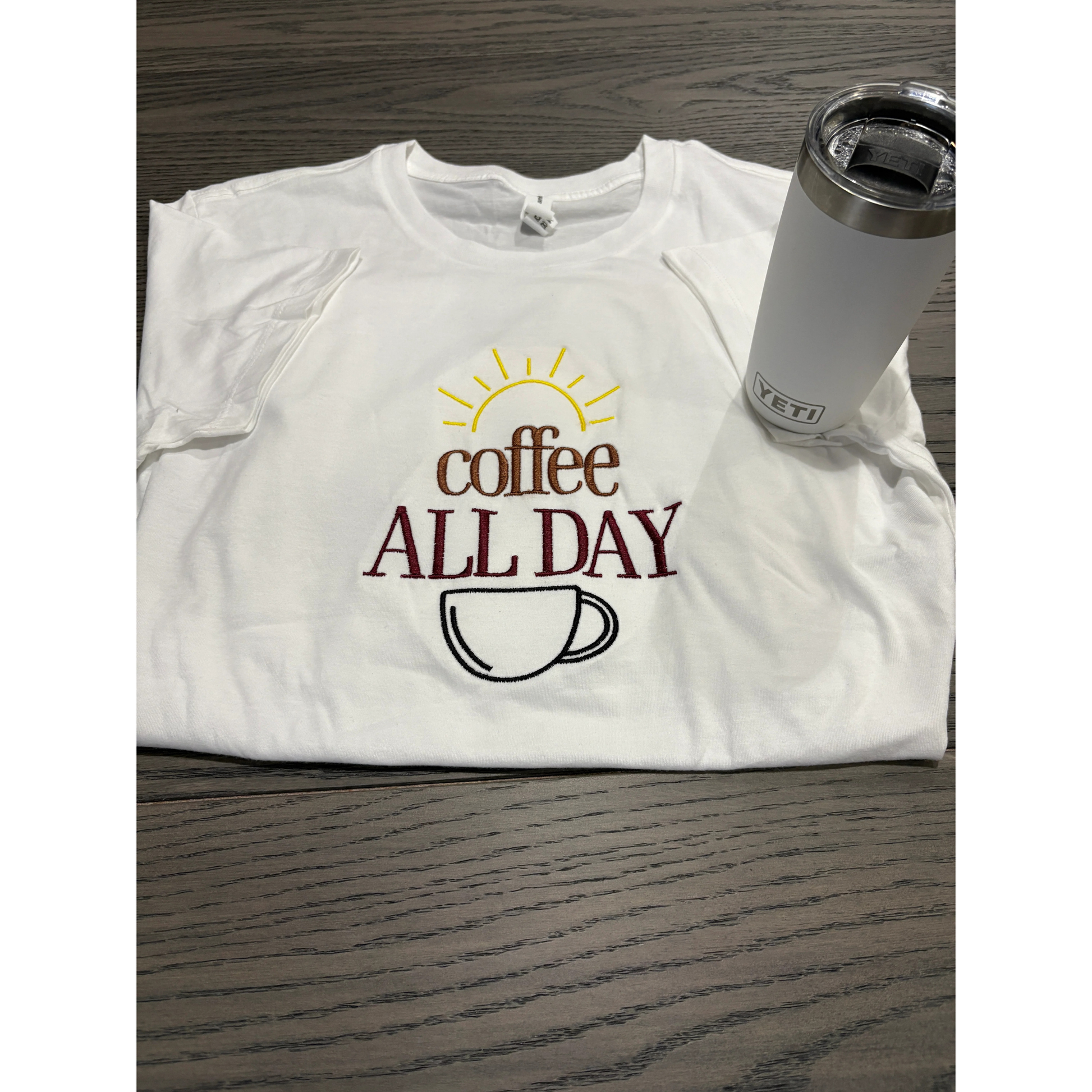 White t-shirt with 'Coffee All Day' design and a Yeti tumbler on a wooden surface
