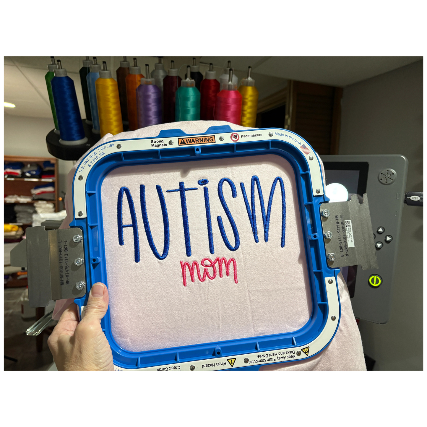 Embroidery machine with 'Autism mom' text on a pink tshirt