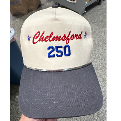 a tan hat with a gray brim with embroidered text chelmsford in red and 250 in blue thread. 