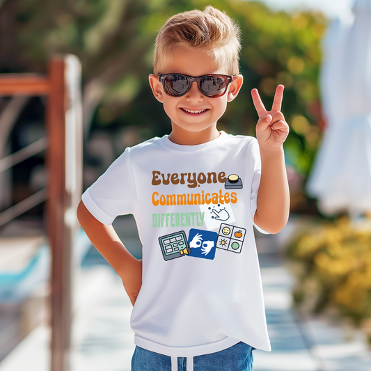 Child wearing a white t-shirt with colorful text and graphics, outdoors.