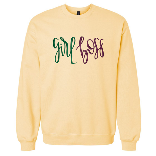 A pale yellow crewneck sweatshirt featuring the text 'girl boss' embroidered across the chest in green and dark purple script.