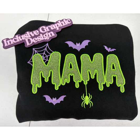 A black sweatshirt applique featuring a Halloween-themed  'MAMA' design in dripping neon green glitter-style lettering, purple bats, a spider, and a spiderweb, shown on a white background with a purple 'Inclusive Graphic Design' brand marker