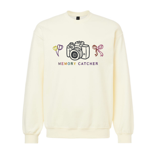 Cream-colored sweatshirt with a camera graphic and 'Memory Catcher' text on a white background