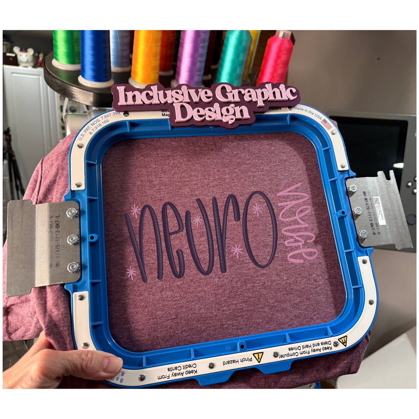 Embroidery hoop with 'neuro' design on a purple fabric, held by a person with colorful thread spools in the background.