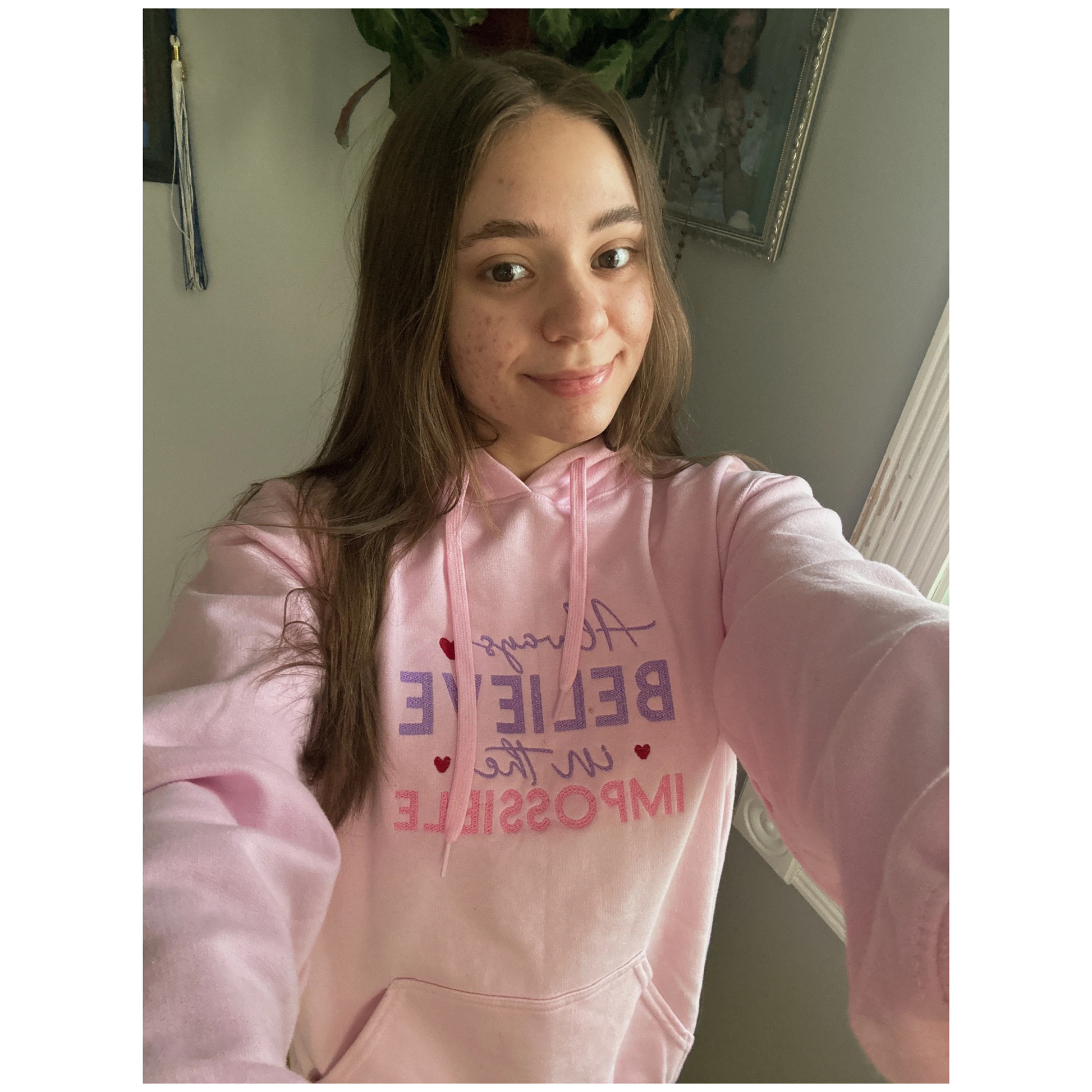 Person wearing a pink hoodie with motivational text, standing indoors.