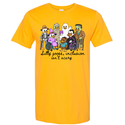 A bright yellow short-sleeve t-shirt with a cartoon illustration of six silly goose characters dressed in Halloween costumes, including a skeleton, witch, mummy, ghost, penguin in a wheelchair, and Frankenstein's monster, with the text 'Silly goose, inclusion isn't scary' below .