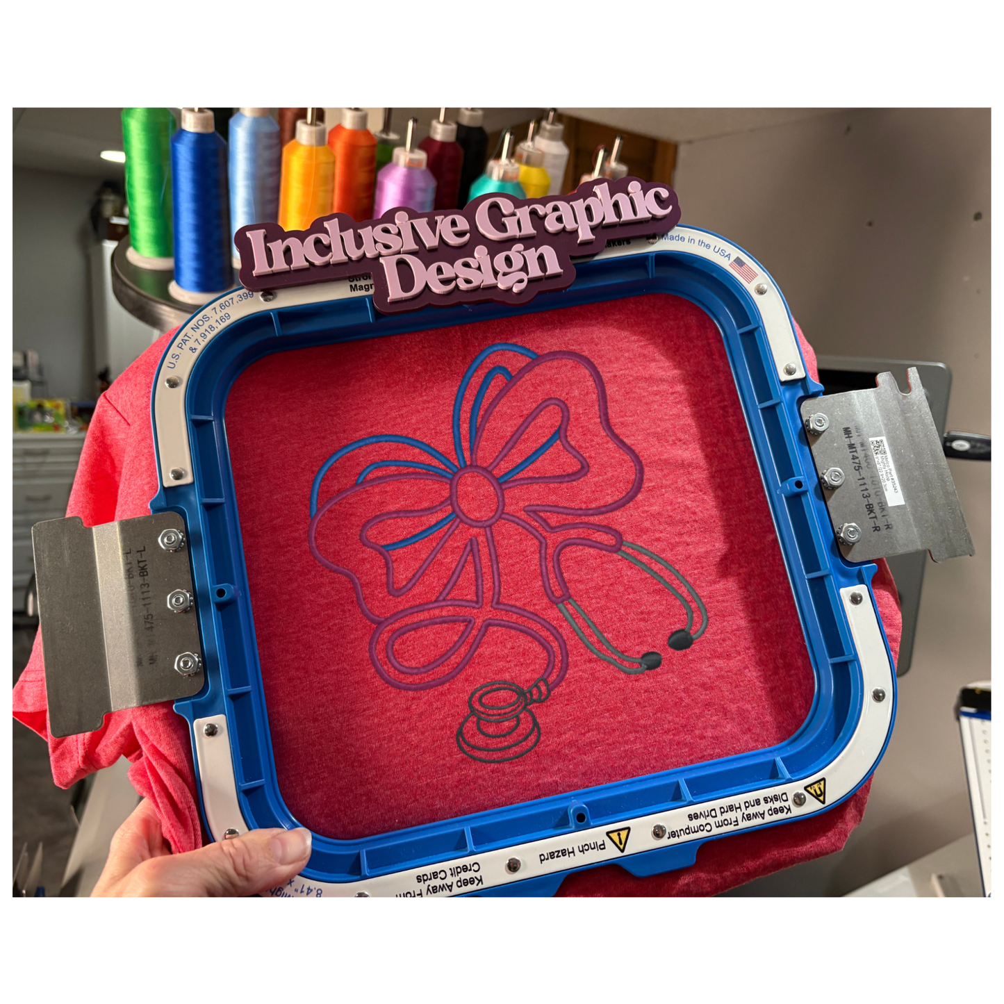 Embroidery hoop with a red fabric featuring a blue bow design, held by a person.