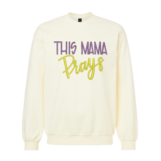 Cream-colored sweatshirt with 'This Mama Prays' text on a white background