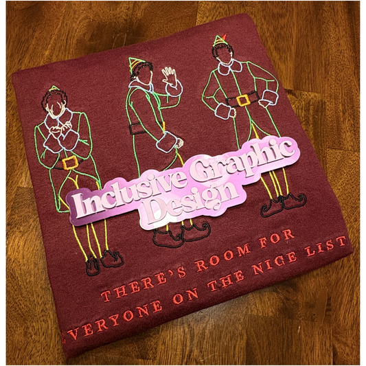 A folded maroon shirt featuring embroidered elf characters and the text 'THERE'S ROOM FOR EVERYONE ON THE NICE LIST', and a magnet with the words Inclusive Graphic Design on the shirt.