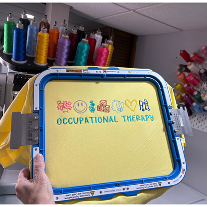 Yellow sweatshirt with 'Occupational Therapy' text and symbols on an embroidery hoop.