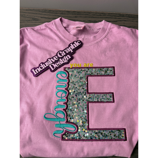 Pink shirt with text and graphics on a wooden surface